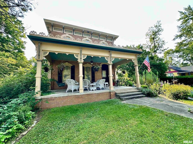 rear view of house featuring a yard and covered porch