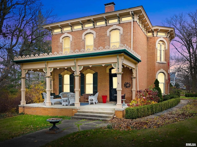 back house at dusk featuring covered porch