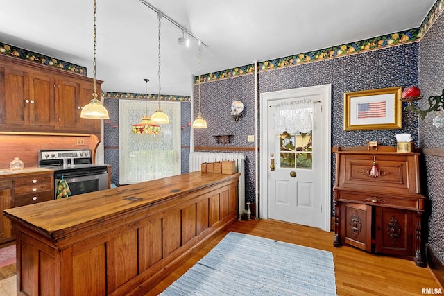 kitchen with rail lighting, hanging light fixtures, light hardwood / wood-style flooring, wooden counters, and stainless steel electric range