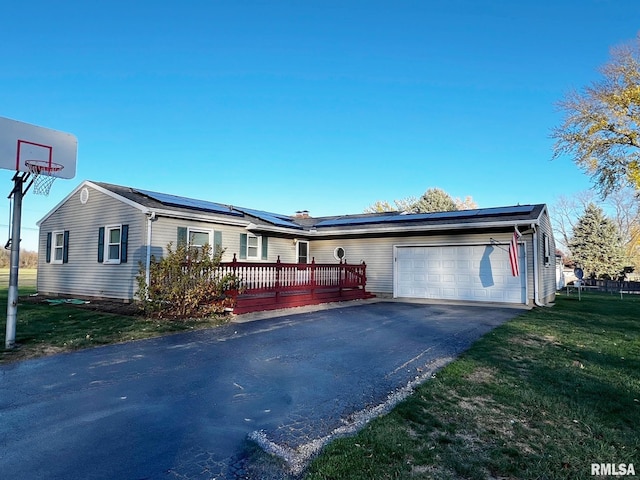 single story home with solar panels, a front lawn, a deck, and a garage