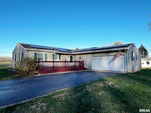 single story home featuring a front yard, solar panels, a deck, and a garage