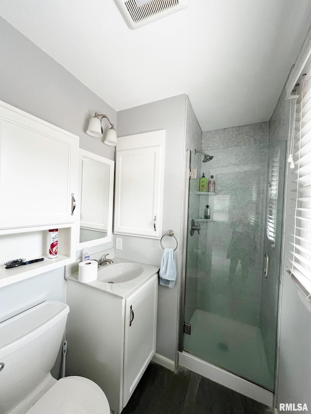 bathroom featuring hardwood / wood-style flooring, vanity, toilet, and a shower with door