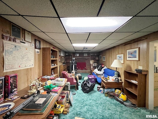 carpeted home office with a drop ceiling and wooden walls