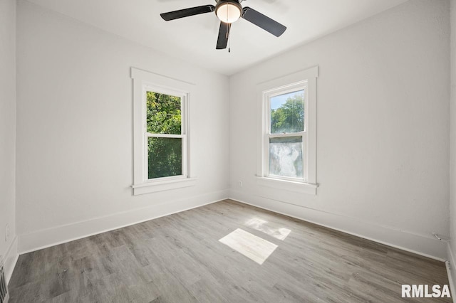 empty room with ceiling fan, a healthy amount of sunlight, and wood-type flooring