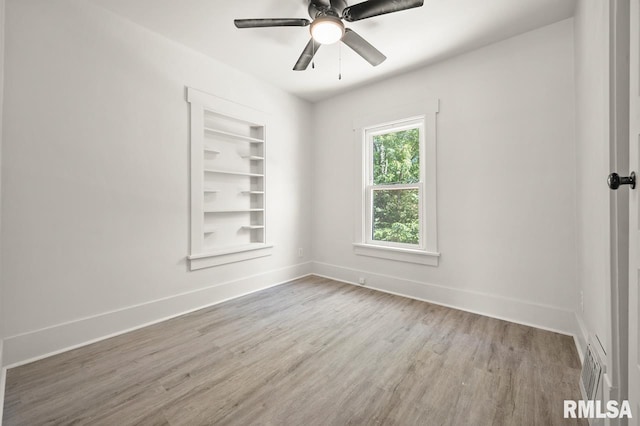 unfurnished room featuring hardwood / wood-style floors, built in shelves, and ceiling fan