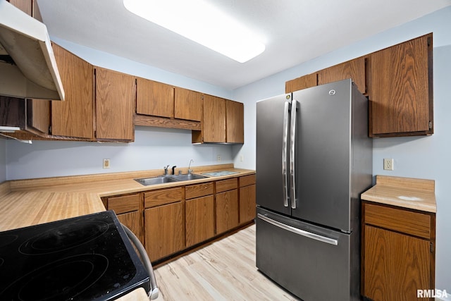 kitchen with stainless steel fridge, sink, light wood-type flooring, and electric stove