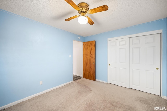 unfurnished bedroom featuring a closet, a textured ceiling, light colored carpet, and ceiling fan