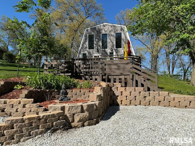 view of front of property featuring stairs, a deck, and a gambrel roof