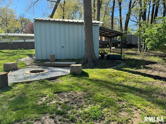 view of shed with fence and a fire pit