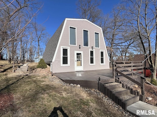 exterior space featuring a wooden deck, a shingled roof, and a gambrel roof