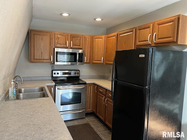 kitchen featuring brown cabinets, stainless steel appliances, a sink, and light countertops