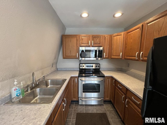 kitchen featuring a sink, stainless steel appliances, light countertops, and brown cabinets