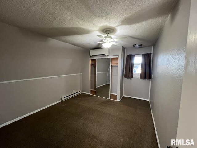 unfurnished bedroom featuring baseboards, baseboard heating, a textured ceiling, an AC wall unit, and dark carpet