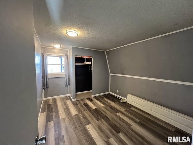 spare room featuring crown molding, a textured ceiling, baseboards, and dark wood-type flooring