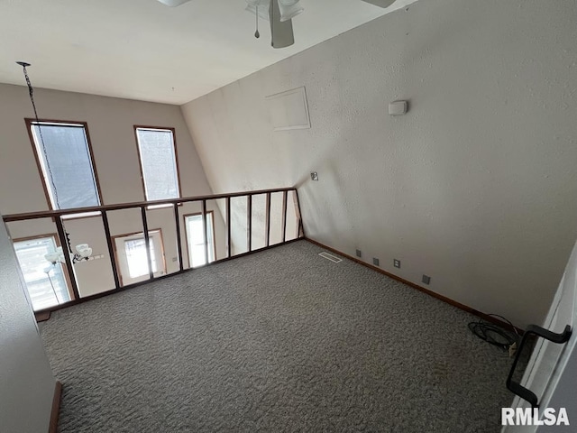 carpeted empty room with baseboards, visible vents, and a ceiling fan