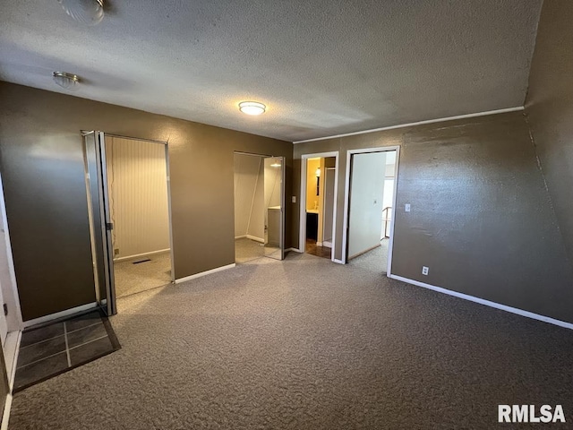 spare room featuring baseboards, a textured ceiling, and carpet flooring