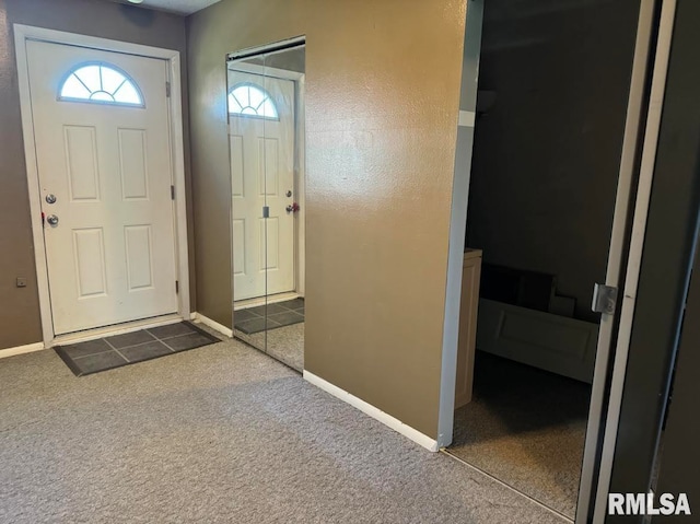 foyer entrance with dark tile patterned flooring, dark carpet, and baseboards