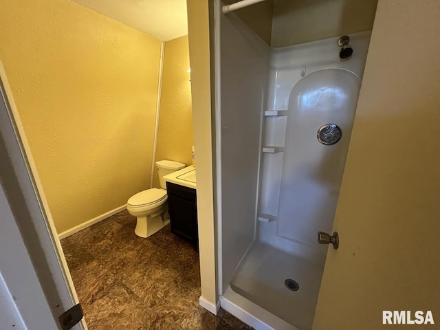 bathroom with toilet, baseboards, a shower, and vanity