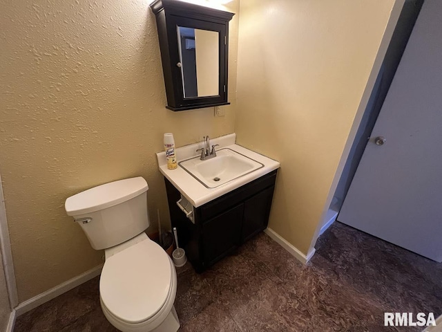 half bath with toilet, baseboards, and vanity