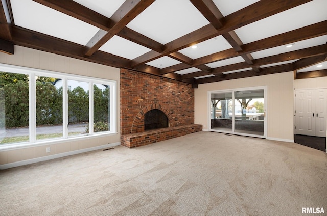 unfurnished living room featuring a fireplace, beamed ceiling, and a healthy amount of sunlight