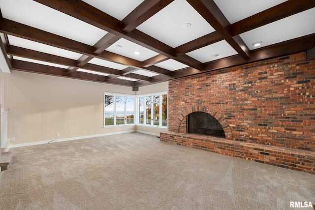 unfurnished living room featuring beam ceiling, a fireplace, carpet floors, and brick wall