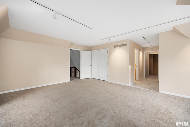 empty room featuring light carpet and track lighting