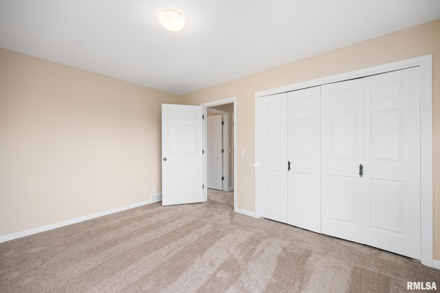 unfurnished bedroom with light colored carpet and a closet