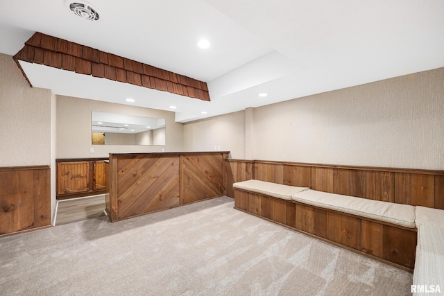 basement with light carpet and wood walls