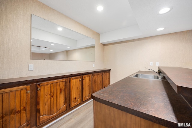 bar with light hardwood / wood-style flooring and sink