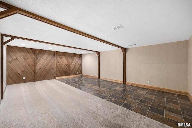 basement featuring a textured ceiling and dark carpet