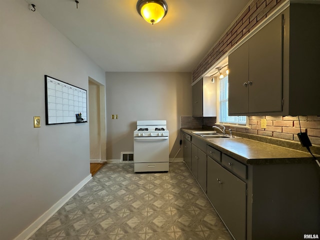 kitchen featuring gray cabinets, decorative backsplash, sink, and white gas range oven