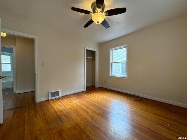 unfurnished bedroom featuring hardwood / wood-style floors, a closet, and ceiling fan