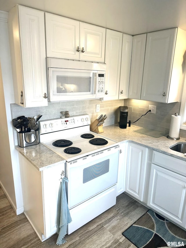 kitchen featuring backsplash, hardwood / wood-style floors, white cabinets, and white appliances