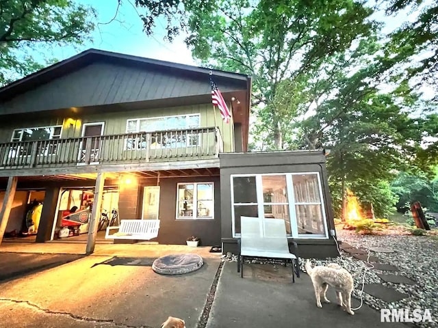 back of property featuring a patio, an outdoor fire pit, and a sunroom