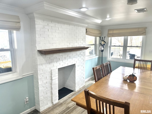 dining room featuring ornamental molding, hardwood / wood-style floors, and a fireplace