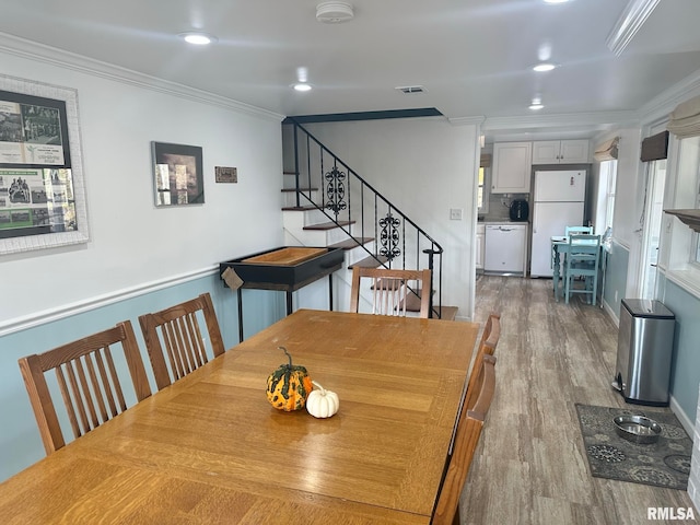 dining room with ornamental molding and hardwood / wood-style flooring