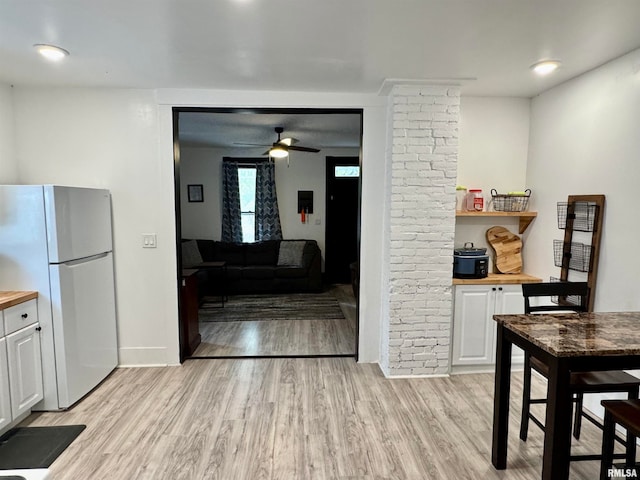 kitchen featuring white cabinetry, butcher block countertops, light hardwood / wood-style flooring, and white refrigerator