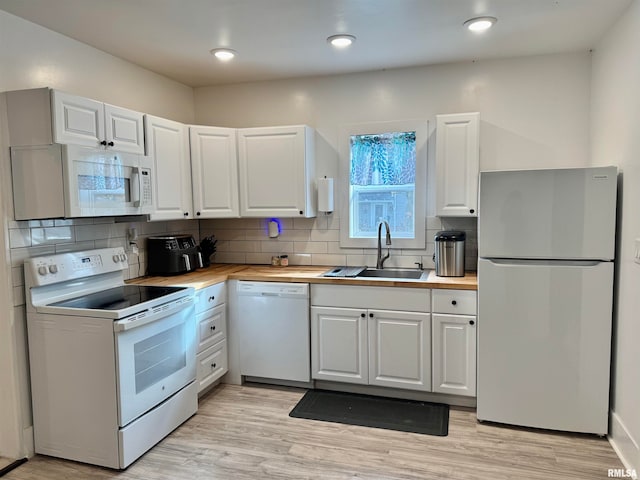 kitchen featuring white appliances, sink, backsplash, light hardwood / wood-style floors, and white cabinets