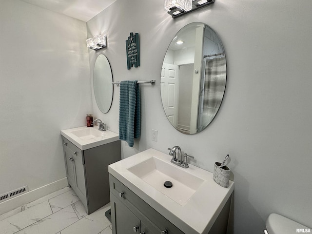 631 S Mcarthur St, Macomb, IL 61455 - full bathroom with two vanities, marble finish flooring, toilet, and baseboards