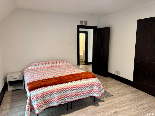 bedroom featuring light hardwood / wood-style flooring and lofted ceiling