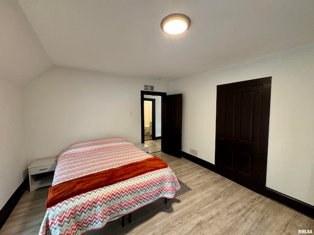 bedroom featuring light hardwood / wood-style floors and lofted ceiling