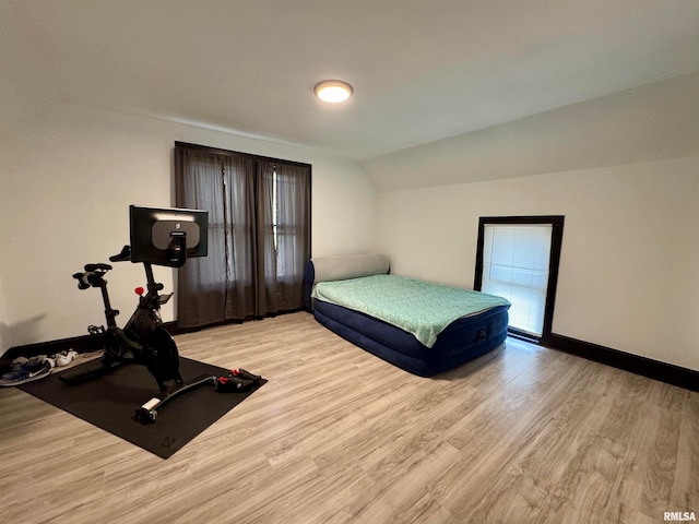 bedroom with light wood-type flooring and vaulted ceiling