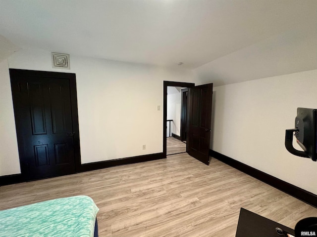 unfurnished bedroom with vaulted ceiling and light hardwood / wood-style flooring