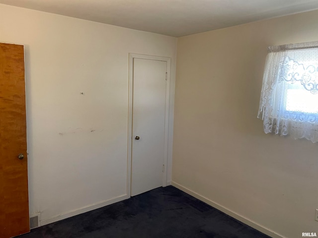 spare room featuring dark colored carpet