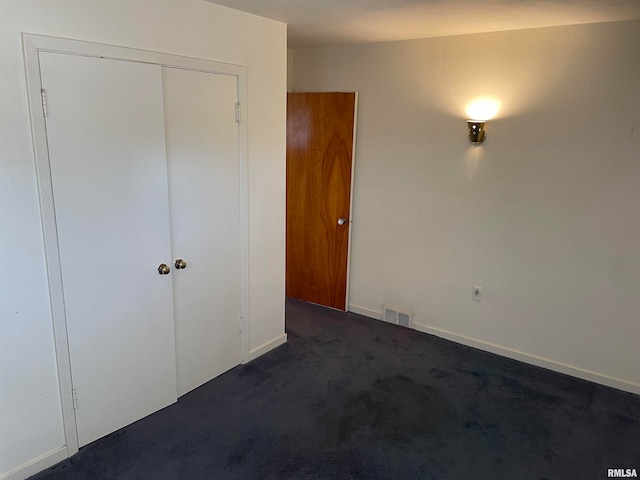 unfurnished bedroom with a closet and dark carpet