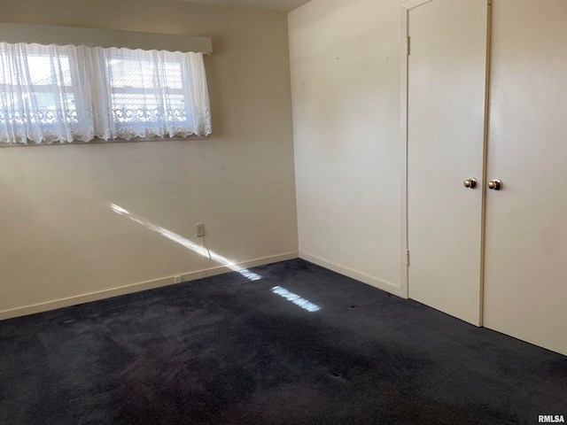 unfurnished bedroom with a closet and dark colored carpet