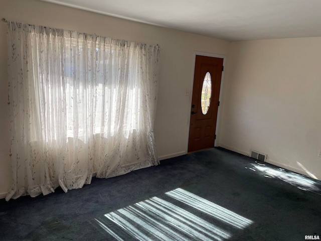 foyer entrance featuring dark colored carpet