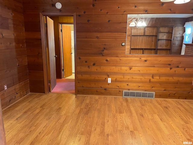 spare room featuring light hardwood / wood-style floors and wood walls