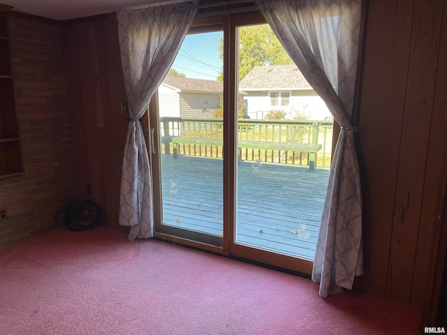 doorway featuring wooden walls and light colored carpet