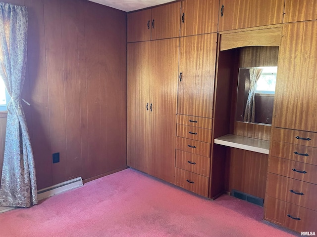 carpeted bedroom with a baseboard heating unit and wood walls